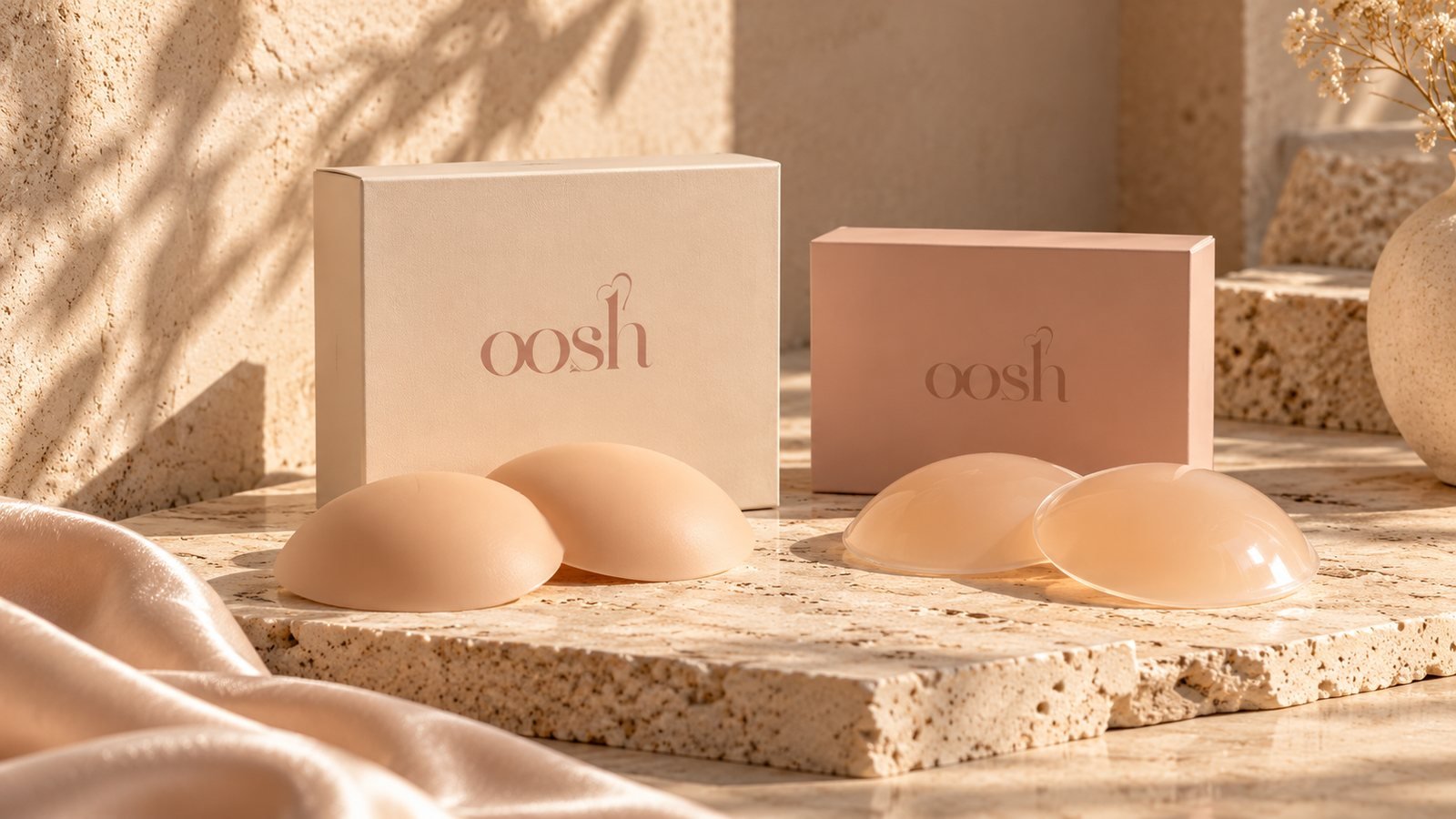 OOsh silicone covers on a stone plinth in warm sunlight, beside a cream and a pink OOsh box